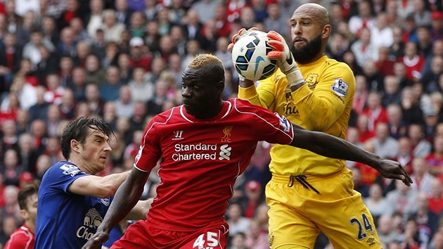 MM! Tim Howard, glman Evertonu, stahuje m ze vzduchu ped Mariem Balotellim z Liverpoolu.