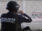 Mexický policista z federálních jednotek si fotí banner na zdi ve mst Iguala,...