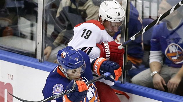 Obrnce Travis Hamonic z NY Islanders tiskne na mantinel tonka Caroliny Jiho Tlustho.