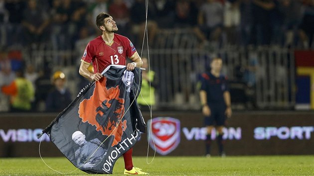 Srbsk stoper Stefan Mitrovi stahuje vlajku Velk Albnie bhem kvalifikanho utkn (14. jna 2014).