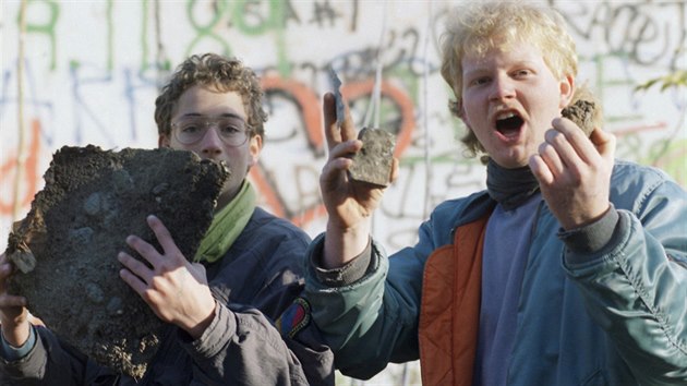 Dva mui hrd ukazuj sti Berlnsk zdi, kter nali u Braniborsk brny po oteven hranic (10. listopadu 1989).