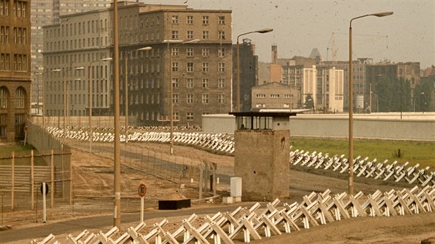 Pásmo smrti v Berlíně roku 1977. Domy v pozadí stojí na území Východního Berlína, v popředí je vidět strážní věž a několikeré zátarasy včetně protitankových ježků (německy Tschechenigel, tedy „české ježky“). Vlastní zeď, natřená nabílo, se táhne vpravo.