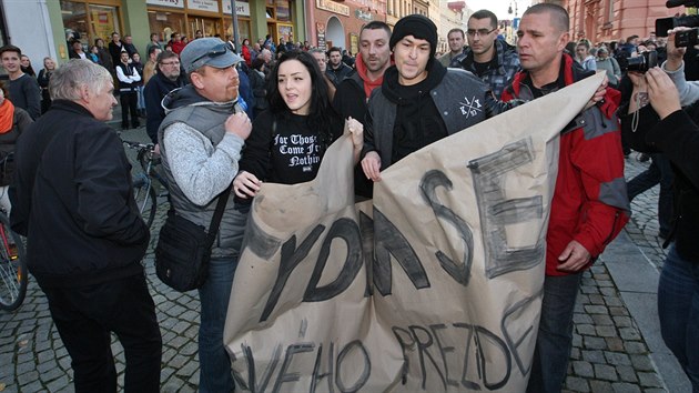 Policist v civilu odvdj stranou dva mlad lidi, kte na mtinku Miloe Zemana v Krnov nesli transparent Stydm se za svho prezidenta. (11. listopadu 2014)