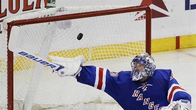 Henrik Lundqvist z New Yorku Rangers se pokou vyrazit puk svou hokejkou.