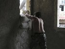 Povstalec dává pytle s pískem do oken na pedmstí Aleppa (6. prosince 2014).