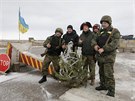 Ukrajintí vojáci a dobrovolníci pózují na kontrolním stanoviti u msta...