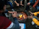 Ilegální imigranti se hřejí u ohně ve svém přechodném táboře u srbské Subotice...