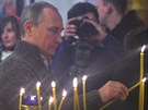 Ruský prezident Putin zapaluje svíku v pravoslavném kostele.