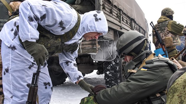 Prorusk separatista (v blm) kontroluje vbavu v batohu ukrajinskho vojka (6. ledna 2015).