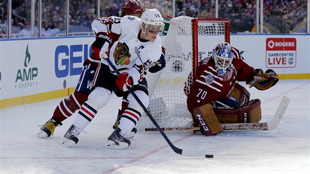 Jonathan Toews (v blm) z Chicaga se tla ped washingtonskho glmana Bradena Holtbyho.