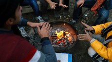 Ilegální imigranti se hejí u ohn ve svém pechodném táboe u srbské Subotice...
