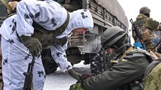 Proruský separatista (v bílém) kontroluje výbavu v batohu ukrajinského vojáka...