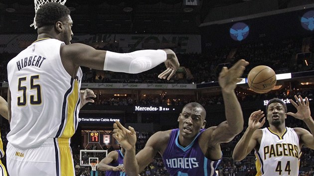 Roy Hibbert (55) z Indiany pihrv na spoluhre Solomona Hilla (44). M se pokou polapit Bismack Biyombo z Charlotte.