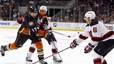 Ryan Kesler z Anaheimu elí dvma soupem z New Jersey. Hokejkou ho strká Adam...