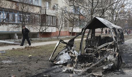 Mu prochází kolem ohoelého vraku auta po raketového útoku v Mariupolu (24....