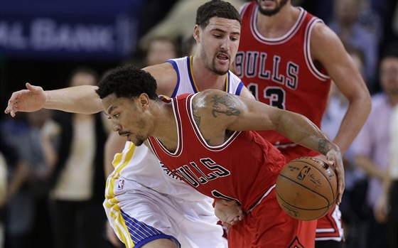 Derrick Rose z Chicaga zkouí projít okolo Klaye Thompsona z Golden State.