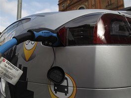 Elektromobil stoj� p�i dob�jen�  na chodn�ku. Na silnici z druh� strany je...