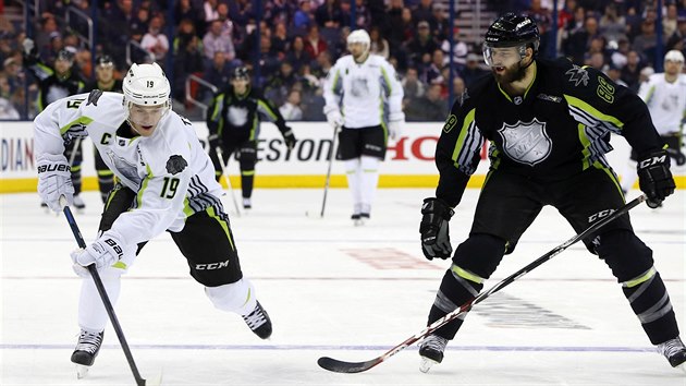 tok vede Jonathan Toews (vlevo), sleduje hoBrent Burns.