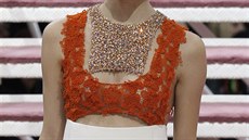Detail bílých vlněných šatů, jejichž vrchní část tvoří oranžová krajka guipure...