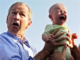 U.S. President George W. Bush hands back a crying baby that was handed to him...