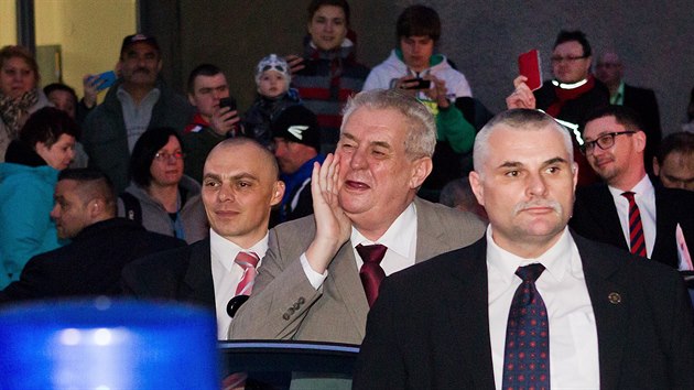 Kromě řady příznivců přivítalo Miloše Zemana v Dobrušce i několik lidí s červenými kartami a píšťalkami. Mluvčí prezidenta Jiří Ovčáček (vpravo vzadu jim to vrátil a také na ně vytasil červenou kartu (18.2.2015).
