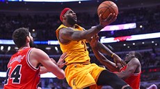 Le Bron James z Clevelandu zakonuje mezi dvojicí Nikola Miroti (vlevo), Tony...