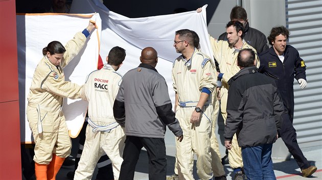 JAK JE NA TOM. Zdravotnci zakrvaj Fernanda Alonsa z tmu McLaren, kterho po nehod pi testovn na okruhu Catalunya pemisuj do vrtulnku.
