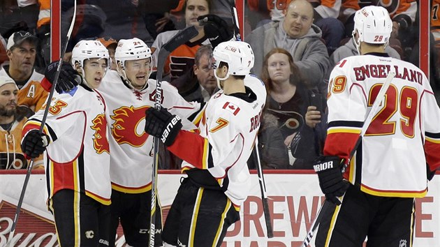 Ji Hudler (druh zleva) z Calgary se raduje se spoluhri Johnnym Gaudreauem (vlevo) a T.J. Brodiem z glu v zpase s Philadelphi. Pijd k nim Deryk Engelland.