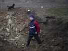 Chlapec z východoukrajinského ermalyku prolézá kráter, který zstal po bojích...