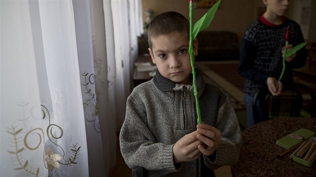 Chlapec z dtskho domova ve vchodoukrajinskm Charcyzku dr paprovou kvtinu, kterou vyrobil k Mezinrodnmu dni en (7. bezna 2015).
