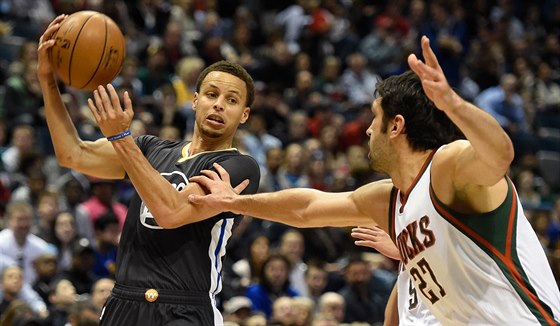 Stephen Curry z Golden State kouzlí s míem, brání ho Zaza Pachulia z Milwaukee.