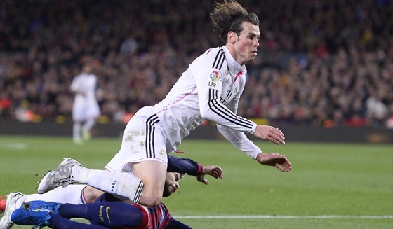 Gareth Bale z Realu Madrid padá po stetu s barcelonským Gerardem Piquem.