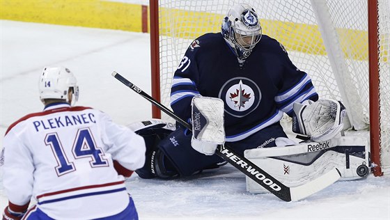 Ondej Pavelec z Winnipegu zasahuje ped Tomáem Plekancem z Montrealu.