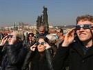 Lidé sledují ástené zatmní Slunce na Karlov most v Praze. (20. bezna 2015)