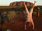 Nahý stojka ped posvátnou horou Uluru v Austrálii