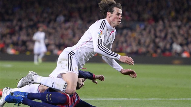 Gareth Bale z Realu Madrid pad po stetu s barcelonskm Gerardem Piquem.