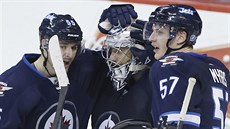 Branká Ondej Pavelec pijímá od spoluhrá z Winnipegu gratulace k istému...