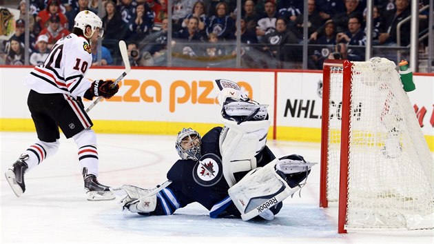 Brank Ondej Pavelec z  Winnipegu el njezdu chicagskho Patricka Sharpa.