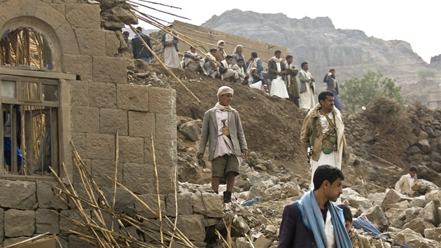 Jemenci stoj na troskch dom ve vesnici pobl Sanaa, kter byly znieny pi nletech koalice veden Sadskou Arbii (4. dubna 2015).