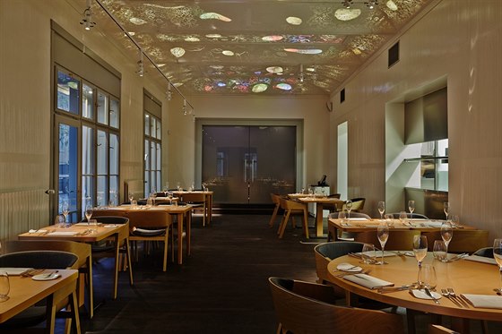 Jednoduchý interiér restaurace zdobí svtelné aplikace na stropu.