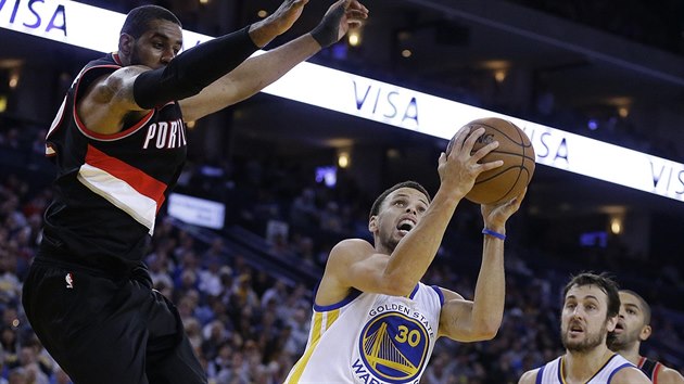 Stephen Curry z Golden State zakonuje, nad nm se vzn LaMarcus Aldridge z Portlandu.