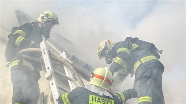 Hasiči rozebírají střešní konstrukci při nedělním požáru rodinného domu v Ivanovicích na Hané a dohašují lokální ohniska. (13. 4. 2015)