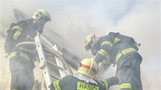 Hasiči rozebírají střešní konstrukci při nedělním požáru rodinného domu v...
