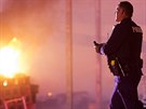 Policista míjí plameny bhem protest v Baltimoru, které vypukly po pohbu...