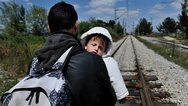 Uprchlík s dítětem kráčí po železnici na hranici Řecka a Makedonie (21. dubna 2015)