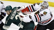Corey Crawford, branká Chicaga, odstrkuje Nina Niederreitera z Minnesoty.