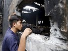 Pracovník továrny v Manile se dívá do ohoelých trosek budovy, kde zemelo...