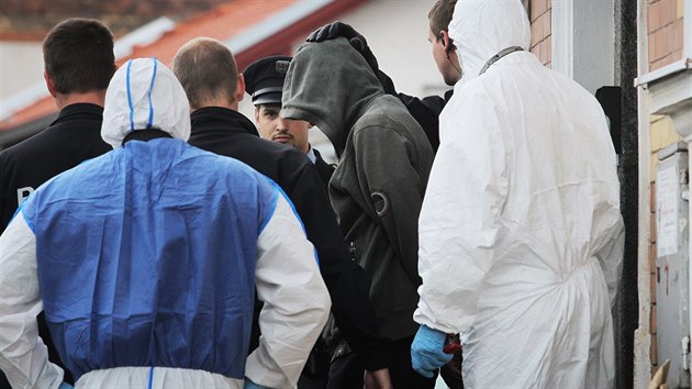 Policisté vedou muže (s kapucou přes hlavu), který je z vraždy knihovnice podezřelý. Zadrželi ho na nádraží v Horní Bříze krátce po činu. (25.5. 2015)