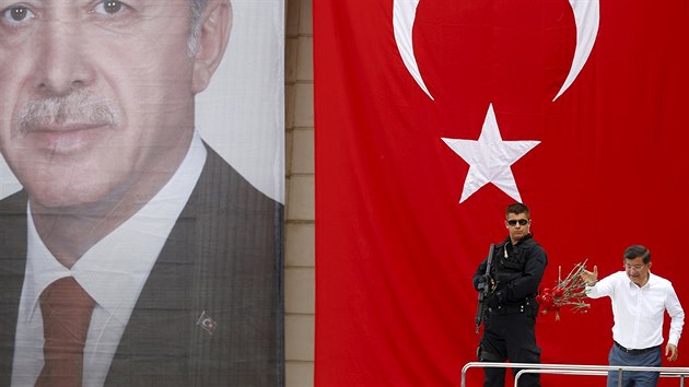 Tureck premir Davutoglu na setkn s pznivci AKP, za nm tureck vlajka a portrt prezidenta Erdogana (3. ervna 2015).
