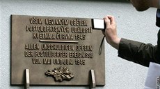 Bronzová pamtní deska pipomíná obti postoloprtského masakru.